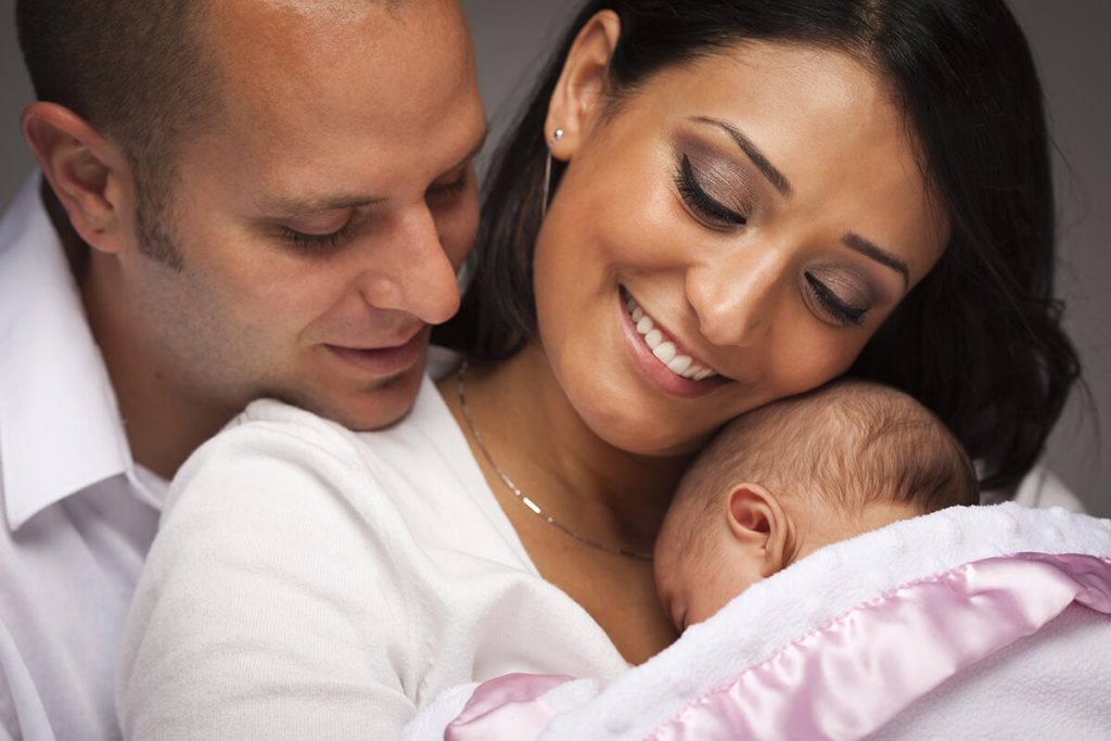 parents holding newborn in a blanket