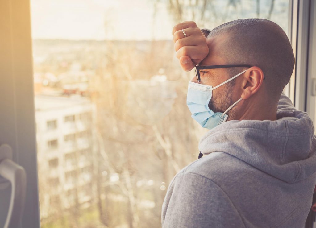 man in quarantine looking out window