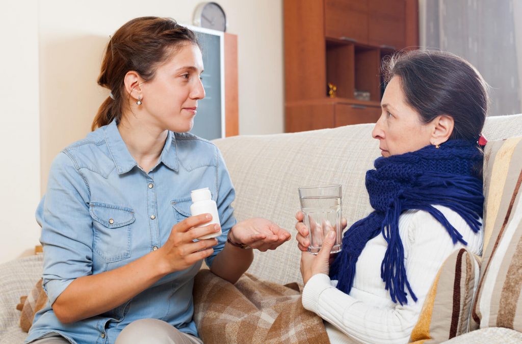 Daughter giving mother medicine