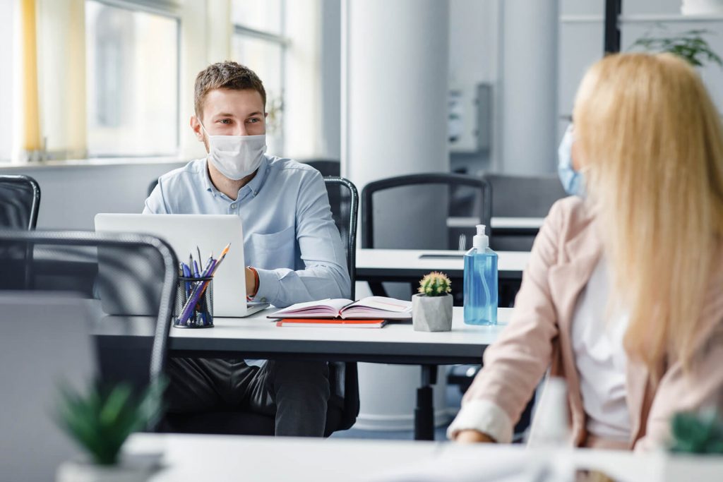 two workers in masks in the office