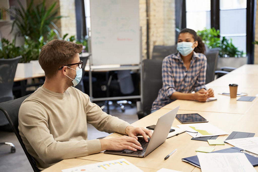 People meeting at work in masks in conference room