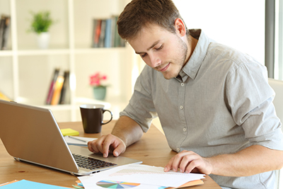 man working from home with spreadsheets