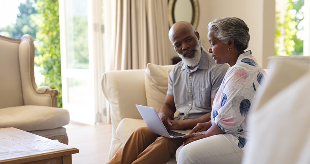 senior couple looking at laptop in their living room