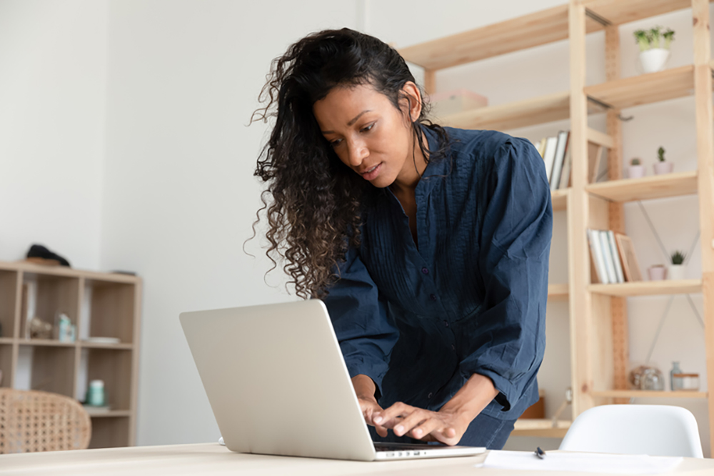 woman standing up by laptop on a desk