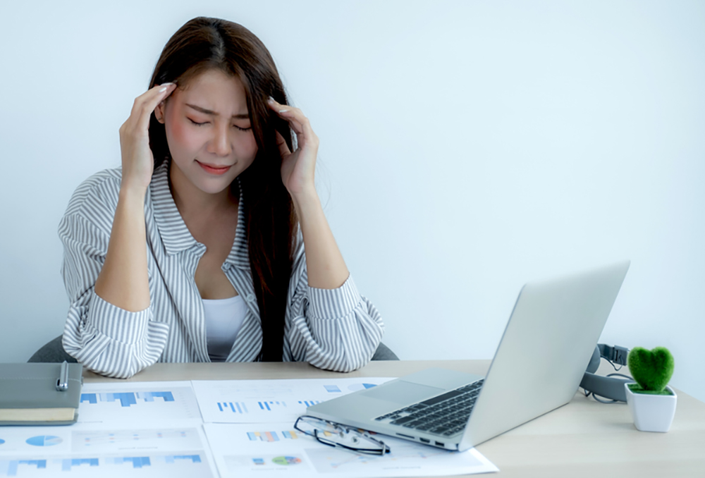 woman holding hands to head at work