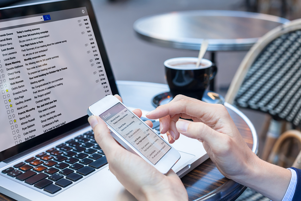 Person looking at emails on computer and phone