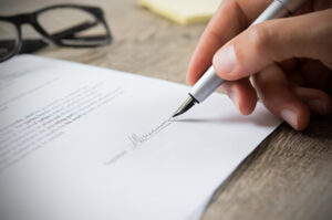 a close up of a person signing a contract